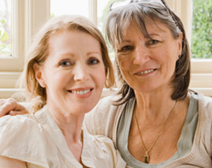 Two women in a side embrace as they smile for the camera.