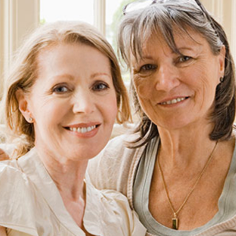 Two women in a side embrace as they smile for the camera.