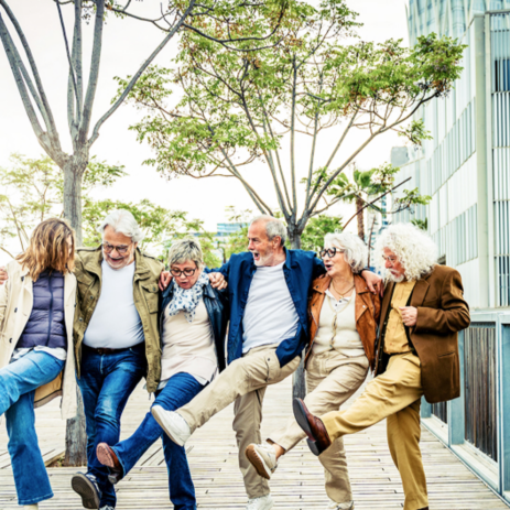 a group of happy seniors lined up as they Cancan kick in unison.