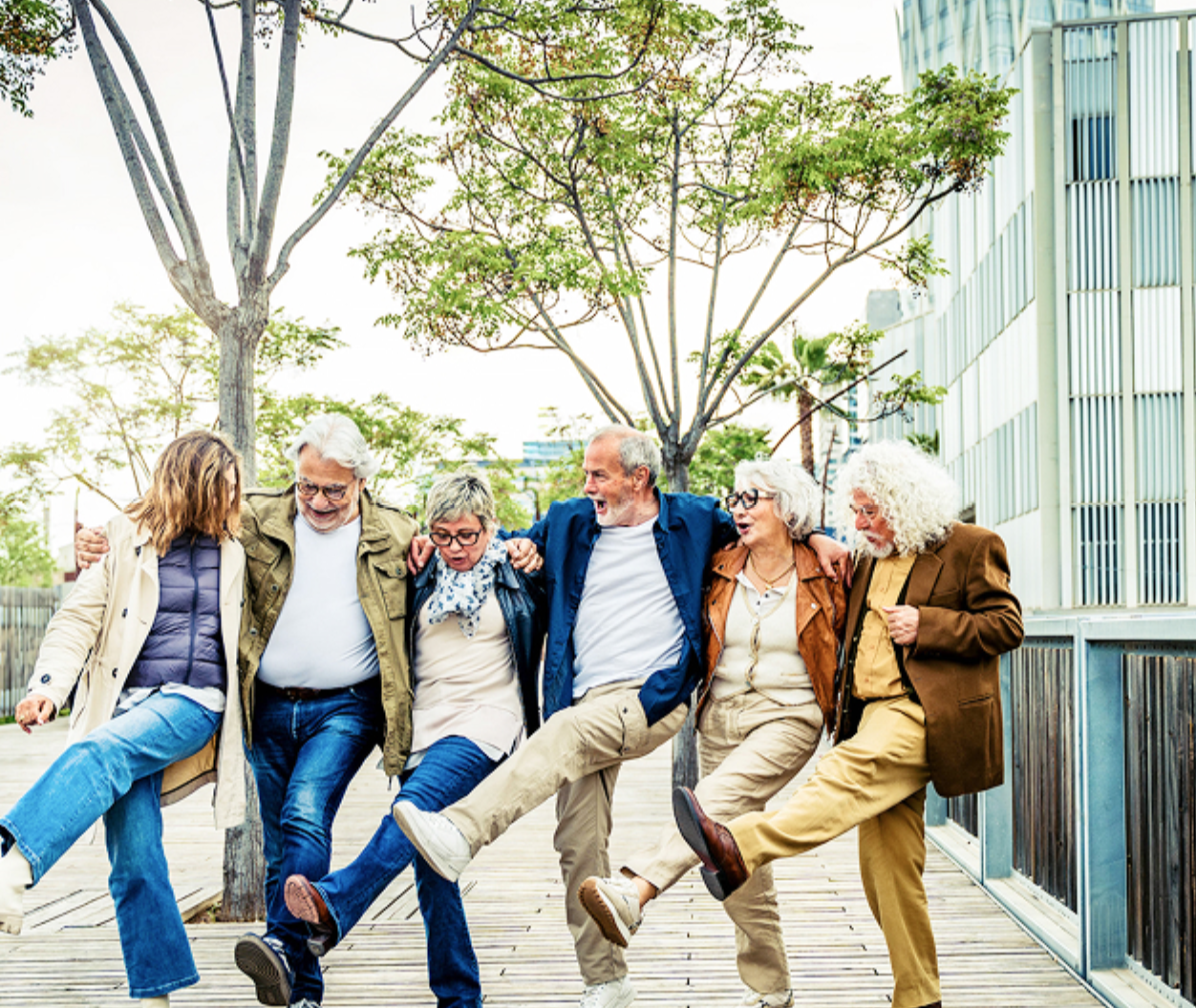 a group of happy seniors lined up as they Cancan kick in unison.