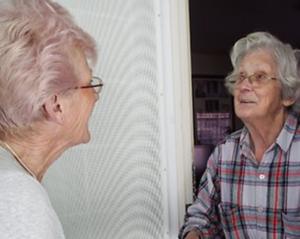 Two elderly women having a conversation in a doorway