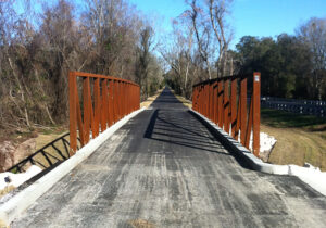 palatka lake butler state trail. Image of a wooden walking bridge with red railing.