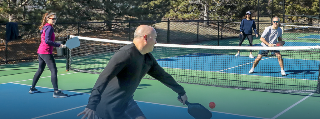 four senior citizens playing pickleball