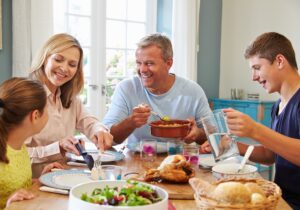 Family gathered around a dining table sharing a meal in a bright home.