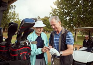 Senior couple polishing a golf club at a golf course.