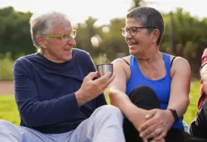 Retired couple sitting outdoors and talking together during a sunny afternoon.