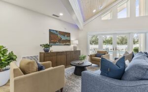 Manufactured home living room with vaulted ceilings, large windows, blue and beige seating, and sliding glass doors opening to the outdoors.