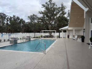 Swimming pool and pool deck at Silver Bay, with lounge seating, a covered area, and community buildings surrounding the pool.
