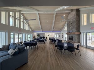 Spacious Silver Bay clubhouse interior with lounge seating, dining tables, large windows, and a stone fireplace.