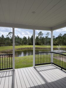 Covered porch at Silver Bay overlooking a pond and wooded landscape.