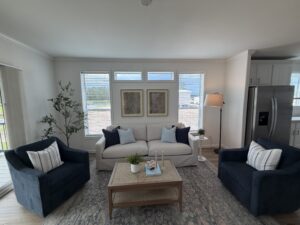Bright Silver Bay living room with two blue armchairs, a light sofa, coffee table, and large windows.