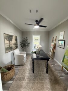 Furnished interior of a Silver Bay model home with a desk, chairs, ceiling fan, artwork, and neutral decor.