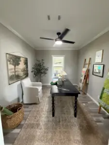 Furnished interior of a Silver Bay model home with a desk, chairs, ceiling fan, artwork, and neutral decor.